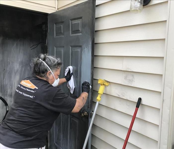 SERVPRO employee wiping a soot-covered door