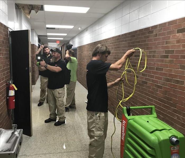 SERVPRO employees assembling their equipment in a hallway