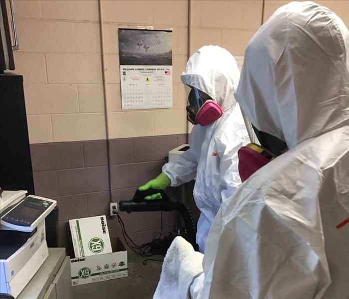 Two SERVPRO employees in PPE in front of equipment