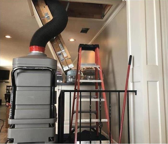 Black tube of gray vacuum enters attic