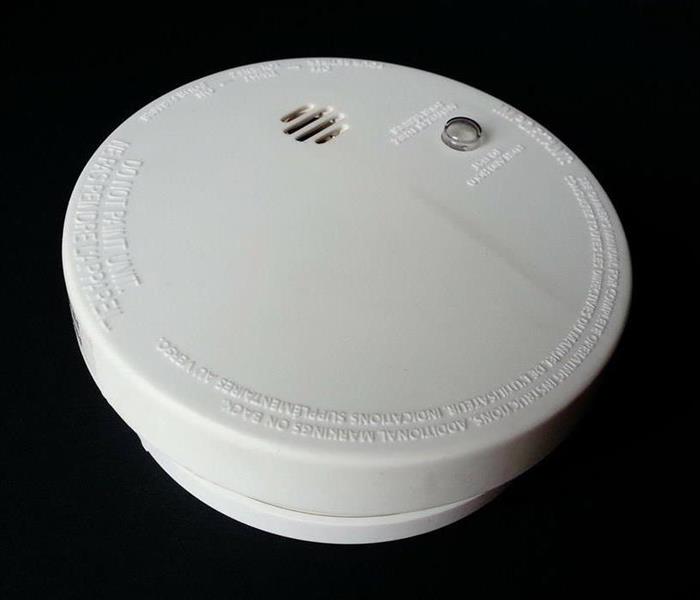Close-up of white smoke detector against black background