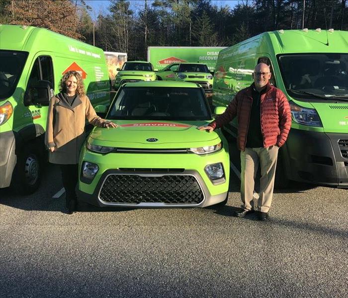Couple pose in front of SERVPRO vehicles