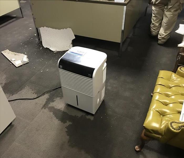 A dehumidifier sitting in the middle of soaked carpet