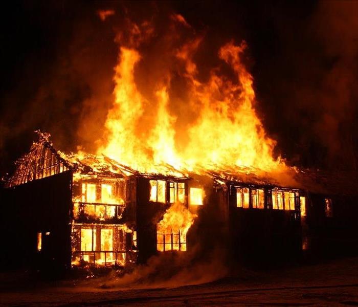 Large house engulfed in flames at night