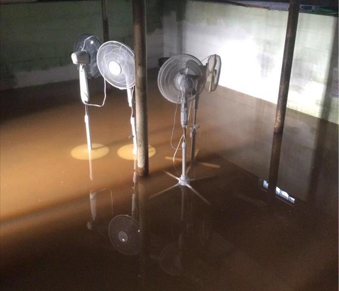Floor fans in standing water in a concrete basement